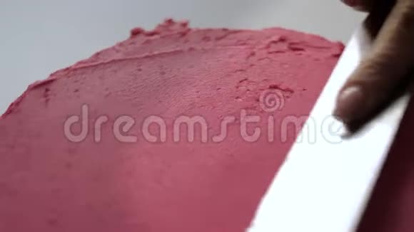 糖果师在蛋糕上放粉红色奶油和糕点匙视频的预览图