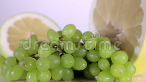 在桌子上旋转的绿葡萄和柠檬片视频的预览图