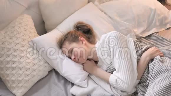 有颈部疼痛的少女躺在床上的俯视图视频的预览图