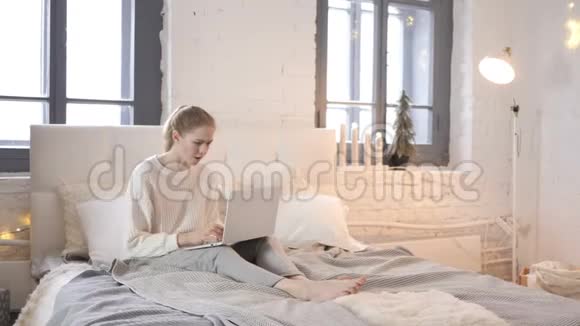 年轻女孩在床上坐着时对笔记本电脑丢失的反应视频的预览图