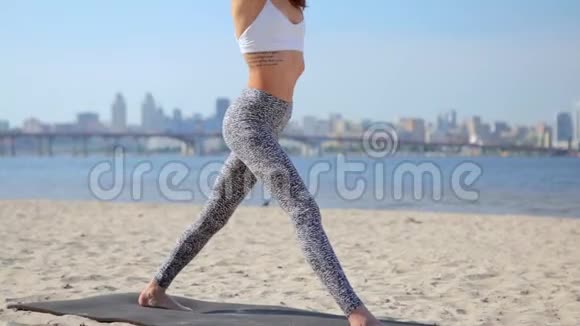 在沙滩上练习瑜伽的女人年轻苗条的运动女子站在瑜伽体式中视频的预览图