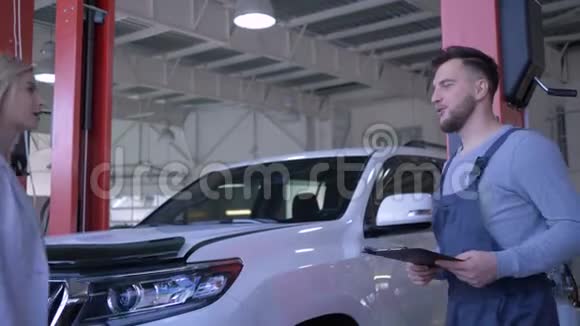 汽车服务客户女性将车辆钥匙交给汽车修理工修理并在后台机器上握手视频的预览图