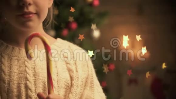 可爱的孩子舔着传统的圣诞糖果微笑着相机装饰发光视频的预览图