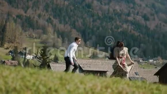 这对幸福夫妇在山上奔跑的特写镜头背景是柔软的木屋视频的预览图