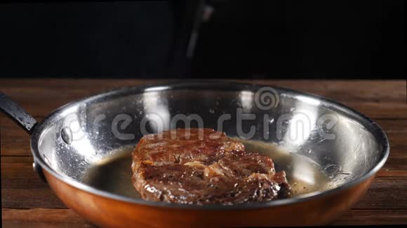 慢镜头的新鲜牛肉牛排与草药在点燃的锅大牛排用炒锅和香料炒视频的预览图