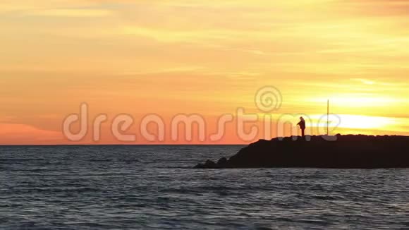 日落时分在防波堤上的渔夫视频的预览图