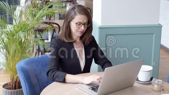 快乐的年轻女商人在咖啡馆里用笔记本电脑视频的预览图