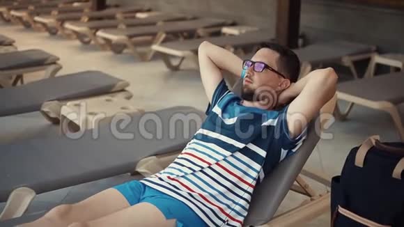 快乐的人正躺在日光浴床上躺在酒店屋顶下的阴影下仰望着视频的预览图