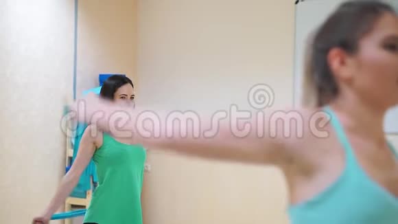 特写一组三个女孩做运动伸展双手橡胶蓝色扩张器视频的预览图