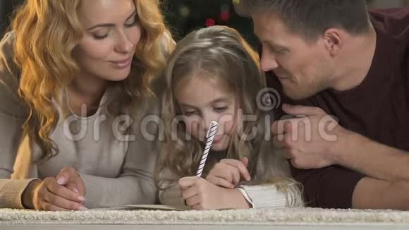 父母帮助女儿写信给圣诞老人微笑着进入相机圣诞节视频的预览图