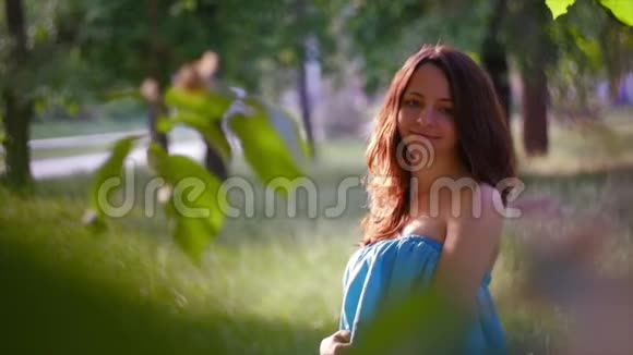 4公里特写镜头绿树枝后面穿蓝色衣服的年轻女子视频的预览图