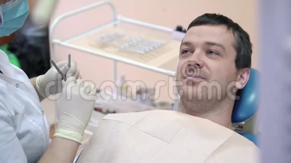 一名男性病人躺在诊所的牙科椅上与医生交谈微笑着准备手术视频的预览图