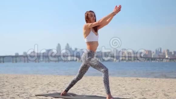 在沙滩上练习瑜伽的女人年轻苗条的运动女子站在瑜伽体式中视频的预览图