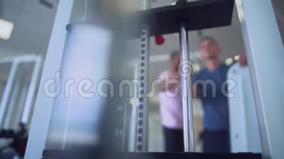 男的在健身房和教练一起举重专注于模拟器健身房里的人健康的生活方式视频的预览图