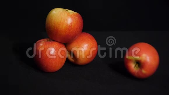 美丽的红苹果在黑色的背景上滚动多汁的水果视频的预览图
