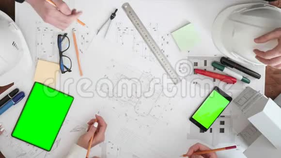 一群人特写讨论和敲定铅笔在桌子上的绘图空间是平板电脑和手机视频的预览图