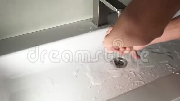 一个年轻人洗了手白色洗脸盆和不锈钢水龙头视频的预览图