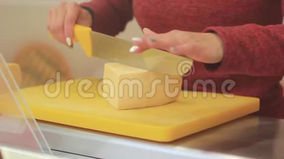 女人的手在木板上用刀切奶酪视频的预览图