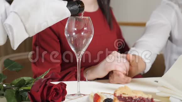 年轻夫妇双手放在桌子上的中弹服务员品尝香槟的慢动作给情侣带来浪漫视频的预览图