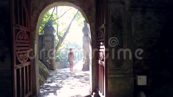 女游客穿过石拱进入洞穴迎着光视频的预览图