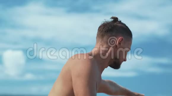 侧景男子做瑜伽站在一条腿上有海洋背景关闭视频的预览图