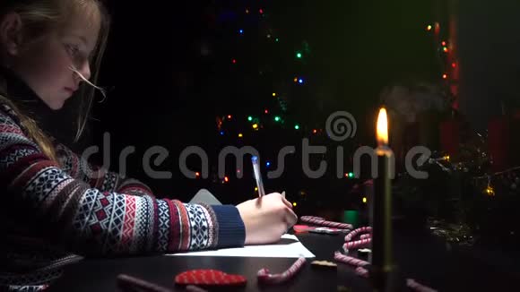 孩子在圣诞前夜给圣诞老人写了一封信信的背景是一棵装饰的节日圣诞树视频的预览图