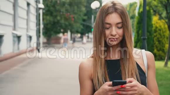 美丽的年轻女子使用她的智能手机走在城市街道上视频的预览图
