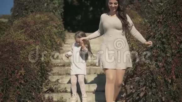 漂亮的妈妈和漂亮的女儿在公园里走下楼梯慢动作视频的预览图
