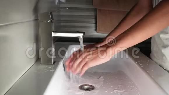 一个年轻人洗了手白色洗脸盆和不锈钢水龙头视频的预览图