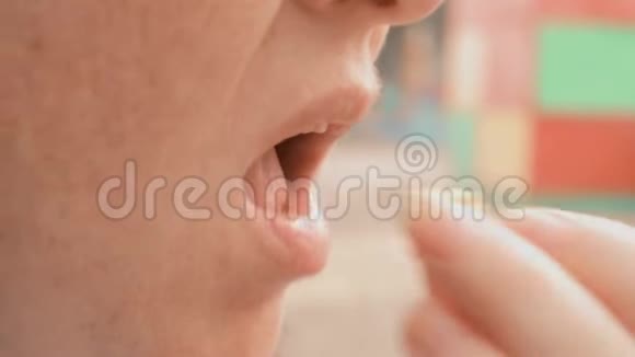 女人的嘴闭上在公园外面吃食物手指把甜爆米花送到嘴里视频的预览图