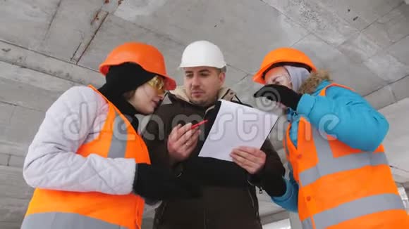 三名土建工程师持有计划并在冬季检查施工现场视频的预览图