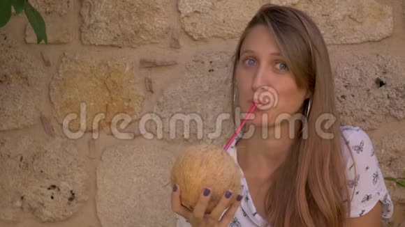 年轻微笑的女人喝椰子水视频的预览图