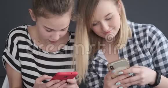 两个十几岁的女孩在讨论和使用智能手机视频的预览图