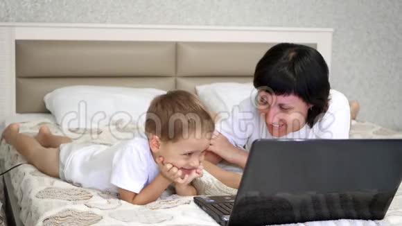 妈妈和她儿子躺在床上用笔记本电脑视频的预览图