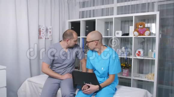 两个医生在检查室里用轮床说话并服用维生素视频的预览图