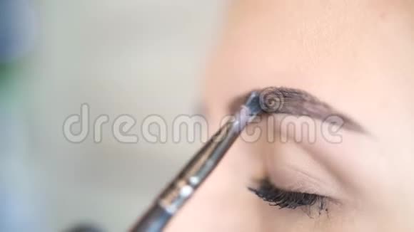 美容师大师正在为年轻女性客户画眉毛上的黑色化妆4慢动作视频的预览图