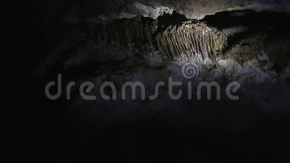 在黑暗的洞穴里点燃手电筒探索仰望钟乳石视频的预览图