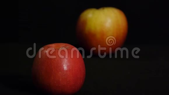 两个红苹果在黑色背景上分离的静止生命快关门重新聚焦视频的预览图