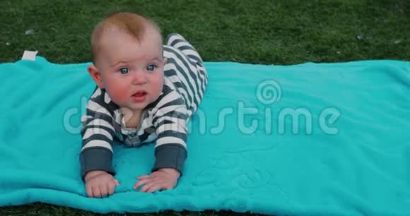 可爱的宝宝躺在草坪上的毛巾上视频的预览图
