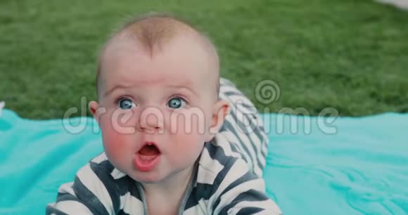 可爱的宝宝躺在草坪上的毛巾上视频的预览图