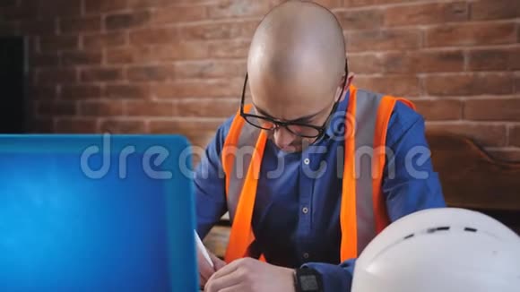 一位年轻建筑师的特写镜头他戴着胡须和眼镜在一个新的建筑项目上用笔记本电脑工作视频的预览图