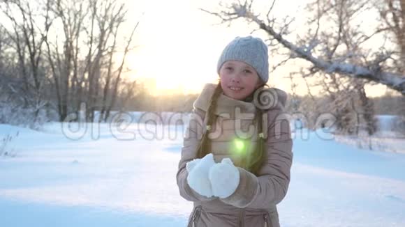 在森林里日落时孩子用双手举起雪雪在阳光下落下闪闪发光快乐的女孩子玩视频的预览图