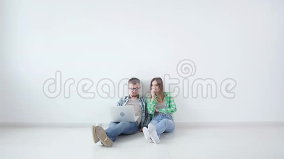 年轻的幸福夫妇正坐在空荡荡的房间里打算在新房子里布置家具视频的预览图