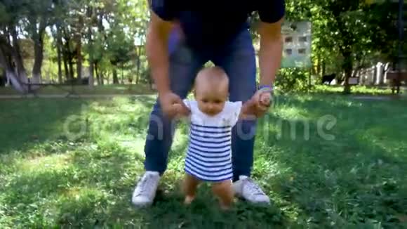 小宝宝学会走路第一步父母在教孩子在草地上迈出第一步视频的预览图