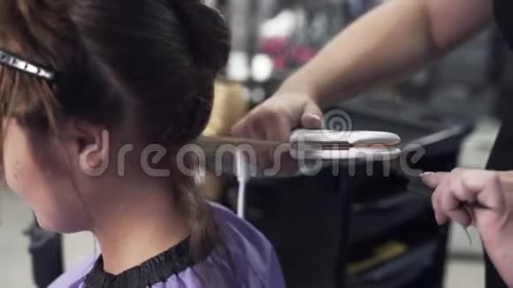 慢镜头拍摄特写steelikam发型设计师用卷发熨斗客户的干发水平梳理一个视频的预览图
