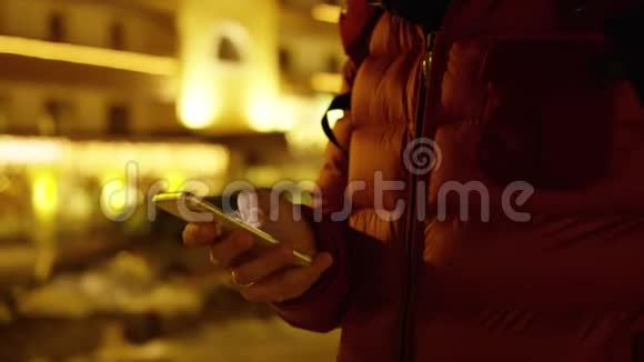 穿红色夹克的无名男子使用他的智能手机冬天的夜晚红色摄像机拍摄视频的预览图