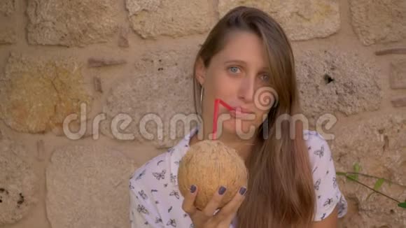 年轻微笑的女人喝椰子水视频的预览图