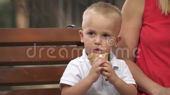 微笑的小男孩在公园长椅上吃冰淇淋视频的预览图
