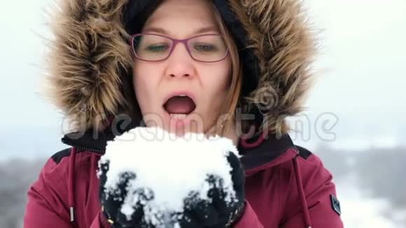 微笑的女人是快乐的在冬天的大自然里吹雪视频的预览图