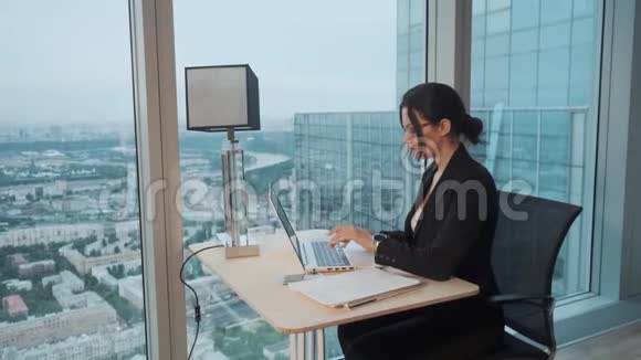 商务女性在一个位于摩天大楼高层的现代化办公室工作在笔记本电脑上工作的漂亮女孩视频的预览图